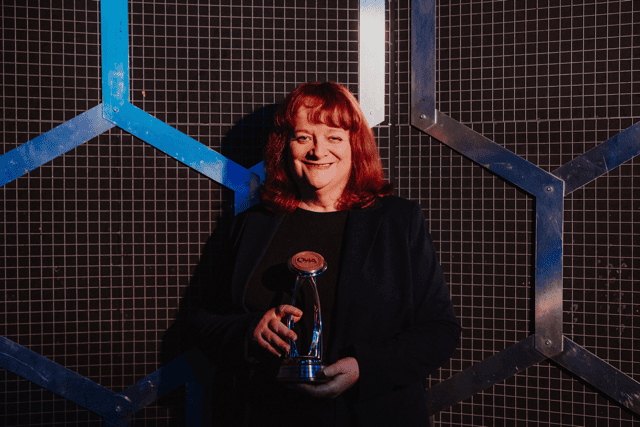 Jo Walker holding an award, smiling